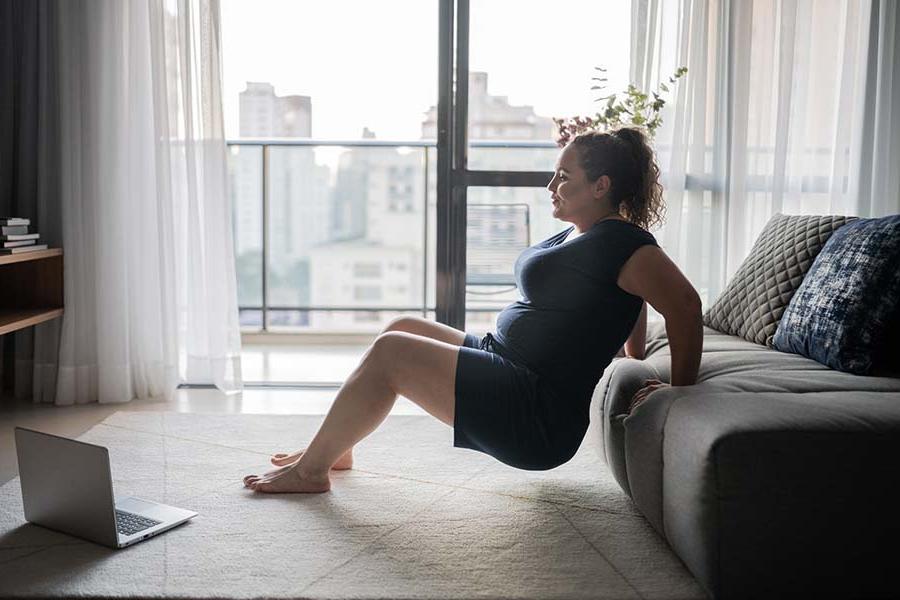 Woman exercising at home, leaning on couch